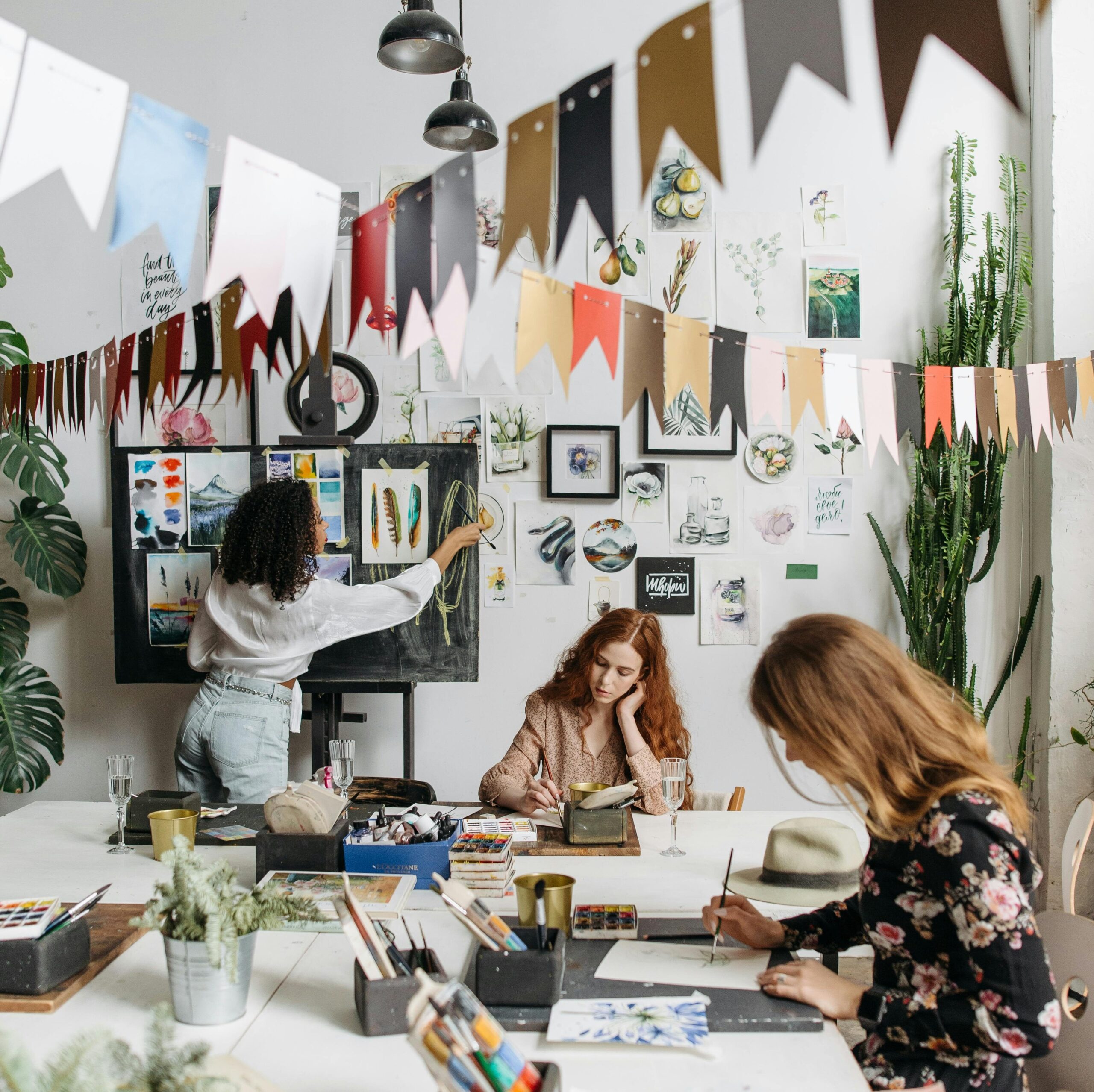 pexels-photo-6925321-6925321 Artists paint in a bright, creative studio adorned with artwork and plants, fostering a vibrant atmosphere.