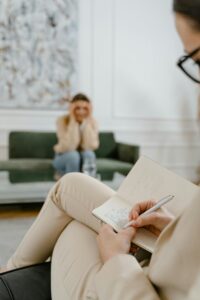 pexels-photo-7699527-7699527 A therapist takes notes in a modern office setting during a therapy session with a patient.