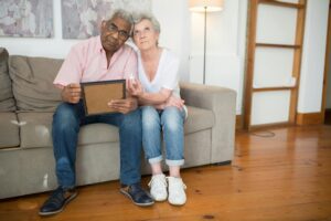pexels-photo-8871539-8871539 Elderly couple reminiscing with a photo frame, sharing a tender moment on the couch.
